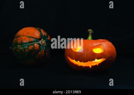 Halloween pumpkin and a small whole pumpkin on the black background Stock Photo