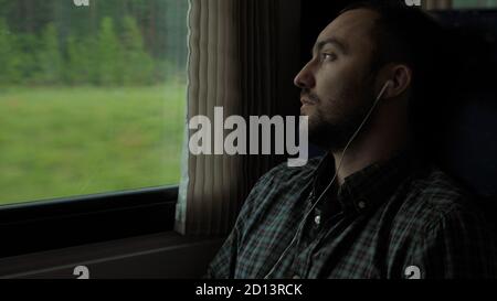 Handsome guy traveling by train, while listening music. Stock Photo