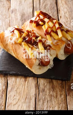 American hot dog polish boy with sausage, cabbage and fries close-up on the table. vertical Stock Photo