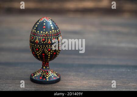 Colorful handmade wooden easter egg on a wooden background. Hand painted easter eggs with acrylic paints, handwork, dot painting, close up, copy space Stock Photo