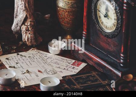 Close up of hand written letters. Old vintage worn postcards with writings in cursive wiccan witch altar. White candles, herbs, tree bark, tarot cards Stock Photo