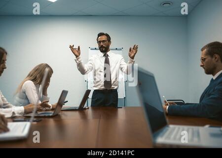 Chief holds business meeting in modern office. Employees sit at table using laptops. Toned image. Close up shot. High quality photo Stock Photo