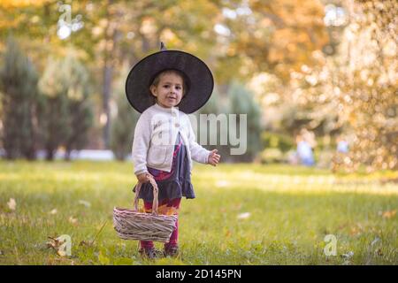 Kids trick or treat on Halloween night. Little girl with pumpkin face candy bucket. Child trick or treating. Kid in scary witch costume with sweets Stock Photo