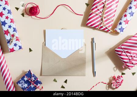 Greating Christmas backdrop with colorful different gift boxes, mockup blank letter to Santa and envelope on a light beige background, copy space with Stock Photo