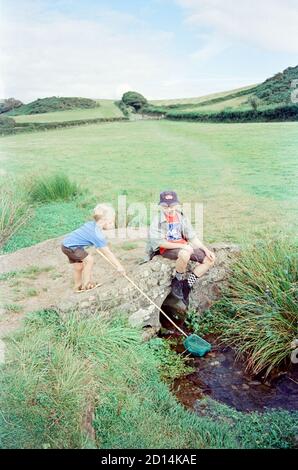Two boys playing in a small stream, Hope Cove, Devon, England, united Kingdom. Stock Photo