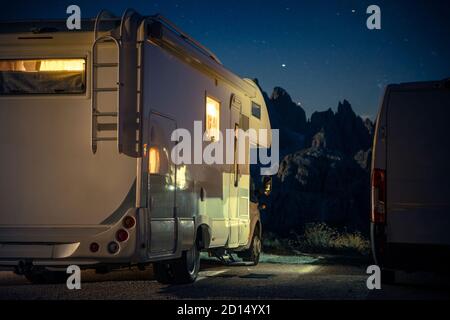 Recreational Vehicle RV Camper Van Camping in the Middle of Alpine Region. Night Time on the Campsite. Scenic View RV Park Pitch. Stock Photo