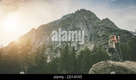Professional Caucasian Landscape Photographer in his 40s Taking Nature Mountains Photos From Large Granite Boulder and Alpine Scenery. Left Side Copy Stock Photo
