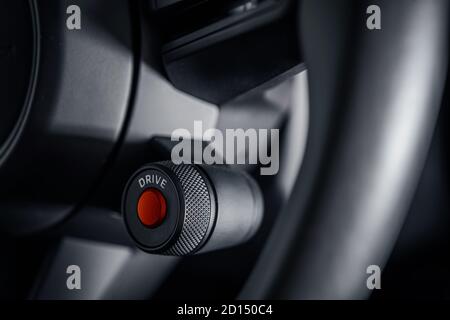 Supercar Engine Ignition Red Push Button Start on the Vehicle Steering Wheel Close Up. Modern Automotive Theme. Stock Photo