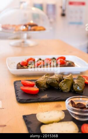 Dolma, delicious Casucasian and Turkish cuisine, vine leaves stuffed with minced meat and rice and italian bruschetta with cherry tomatoes in backgrou Stock Photo