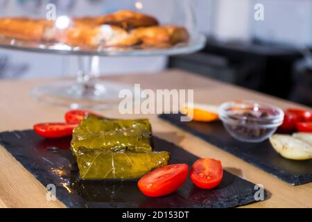 Dolma, delicious Casucasian and Turkish cuisine, vine leaves stuffed with minced meat and rice. Cookies and cheese in background. Stock Photo