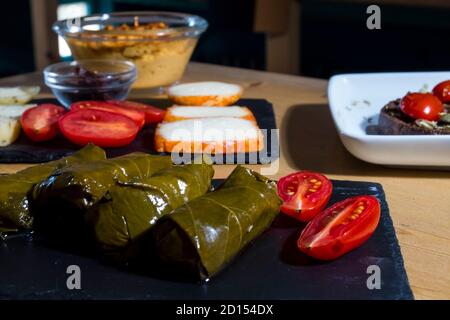 Dolma, delicious Casucasian and Turkish cuisine, vine leaves stuffed with minced meat and rice. traditional hummus cream and cheese in background. Stock Photo