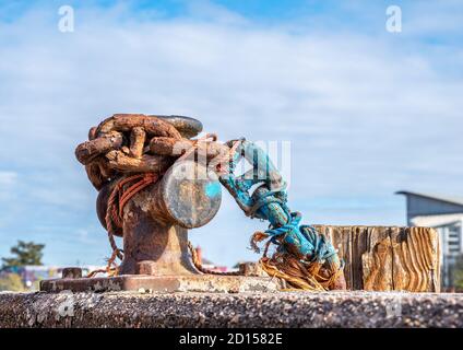 A rusty old chain on a harbour wall capstan. Stock Photo