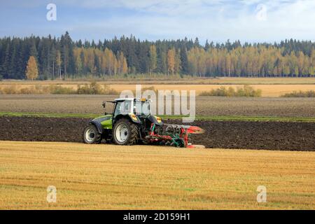Farmer plows field with green Valtra tractor and plough on a sunny autumn morning in South of Finland. Jokioinen, Finland. October 2, 2020 Stock Photo