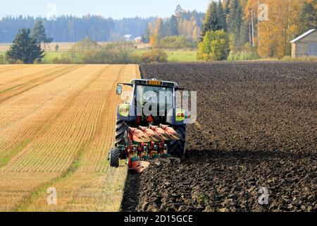 Farmer plows field with green Valtra tractor and plough on a beautiful day of autumn in South of Finland. Jokioinen, Finland. October 2, 2020 Stock Photo