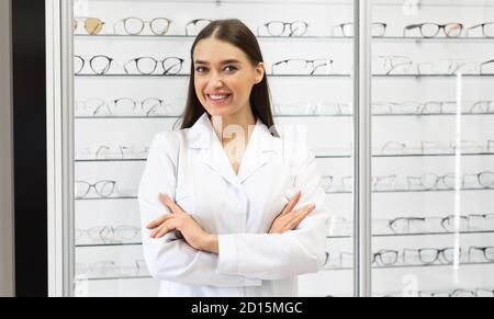 Happy female optometrist standing in optics store Stock Photo