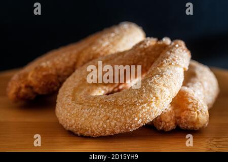 Close up of sweet donuts with sugar and icing on wooden table and black background. Stock Photo
