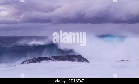 Big wave breaking over rocky coast. Stock Photo
