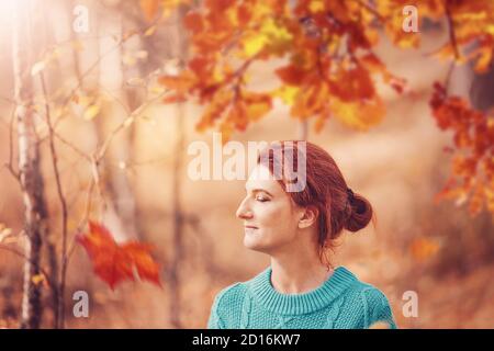 Pretty woman with red hair in autumn forest.