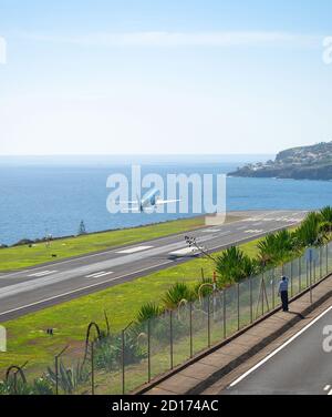 Man watching airplane taking of from runway of Funchal international airport, Madeira, Portugal
