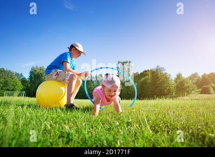 Children are playing on the sport field with hula hoop and rubber fitness ball Stock Photo