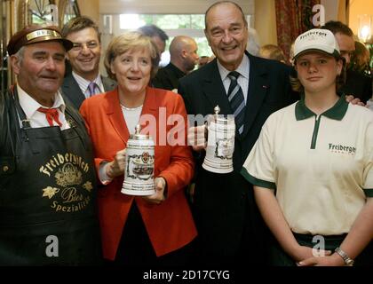 German Chancellor Angela Merkel (2nd L) and French President Jacques Chirac (2nd R) pose with waiters after they received beer mugs as present during their summit in the town of Rheinsberg some 80 kilometres north of [Berlin] June 6, 2006. Merkel and Chirac meet to discuss bilateral and international issues.