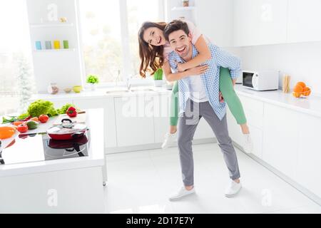 Full length photo of two people brown hair man piggyback redhair girl enjoy weekend hobby supper recipe cuisine wear plaid shirt denim jeans in Stock Photo