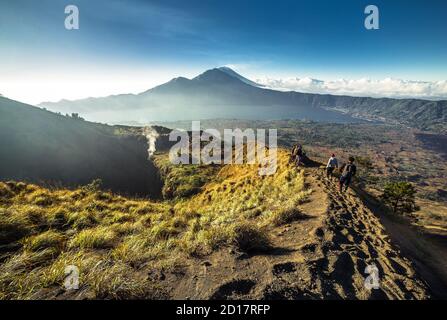 Scenic view of volcano Batur caldera hiking during sunrise. In the background mt.Agung. Ubud, Bali, Indonesia Stock Photo