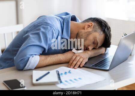 Sleep At Work. Exhausted overworked man employee napping at workplace in office Stock Photo