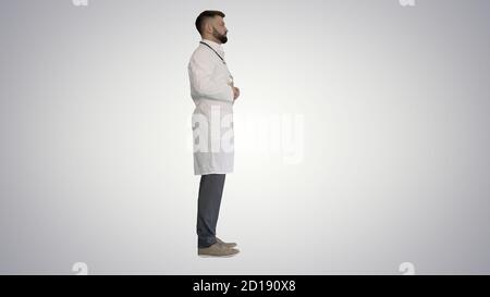 Doctor with a beard standing on gradient background. Stock Photo
