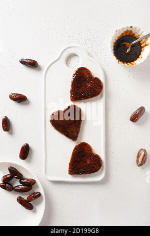 Fresh toasts shaped of heart with dates jam without sugar for tasty breakfast on white table. View from above. Stock Photo