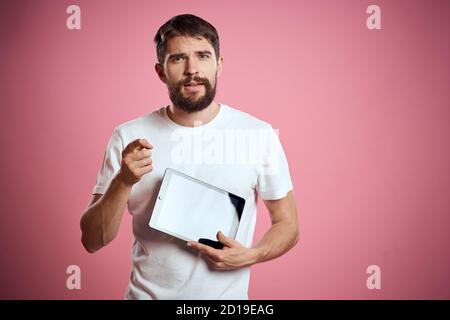 Man advertises a tablet on a pink background codes Space cropped view of emotions white t-shirt model new technologies Stock Photo