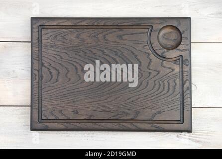 Wooden carved rectangular cutting Board made of oak material, painted in dark color, on a white background. Stock Photo