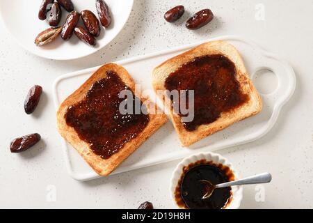 Fresh crispy toasts with dates jam without sugar on white table. Space for text. View from above. Stock Photo