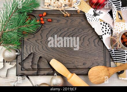 Cutting Board, rolling pin, pine branch and red berries on a light wooden background. Stock Photo