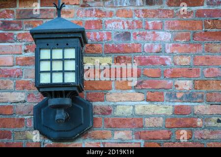 Old steel electric lantern attached to red brick wall Stock Photo