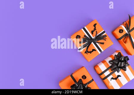 Seasonal Halloween gift boxes decorated with traditional colors orange, black and white on purple background with empty copy space Stock Photo