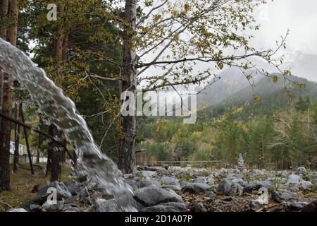 Water Falling from a Pipe Near the Kyngyrga River in Arshan, Russia Stock Photo