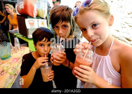 tres niños bebiendo batido de frutas, mercado comarcal, Santanyi, Mallorca, balearic islands, spain, europe Stock Photo