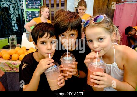 tres niños bebiendo batido de frutas, mercado comarcal, Santanyi, Mallorca, balearic islands, spain, europe Stock Photo