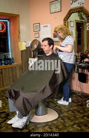 Female hair stylist barber cuts an adult male's hair Stock Photo