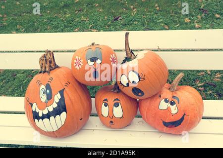 Many pumpinks with painted faces on white porch. Stock Photo