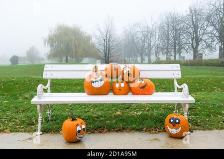 Many pumpinks with painted faces on white porch. Stock Photo