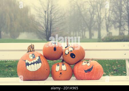 Many pumpinks with painted faces on white porch. Stock Photo