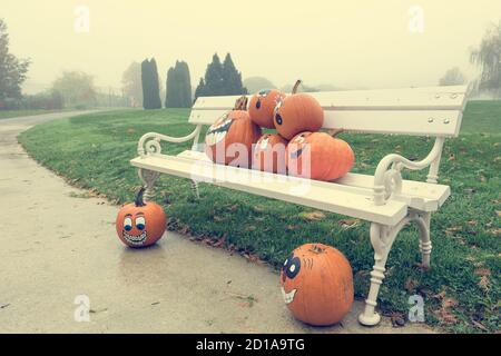 Many pumpinks with painted faces on white porch. Stock Photo