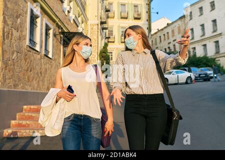 Office workers two women walking, wearing medical protective masks