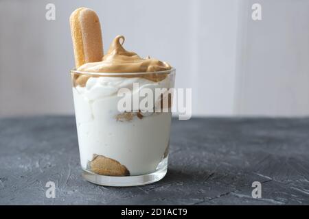 Iced frothy Dalgona Coffee tiramisu, a trendy fluffy creamy whipped coffee on the top of tiramisu dessert. Korean drink latte espresso with coffee foam. Stock Photo