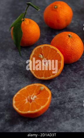 Whole and half  mandarin pieces on a flat surface Stock Photo