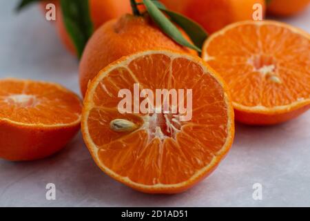 Whole and half  mandarin pieces on a flat surface Stock Photo