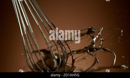 Freeze motion of wire whisk rotating hot melted chocolate, isolated on soft gradient background Stock Photo