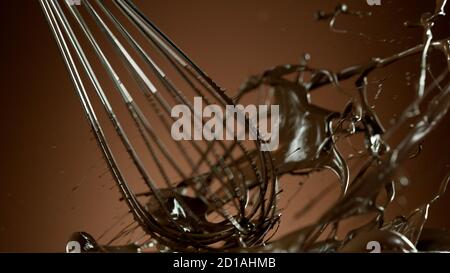 Freeze motion of wire whisk rotating hot melted chocolate, isolated on soft gradient background Stock Photo